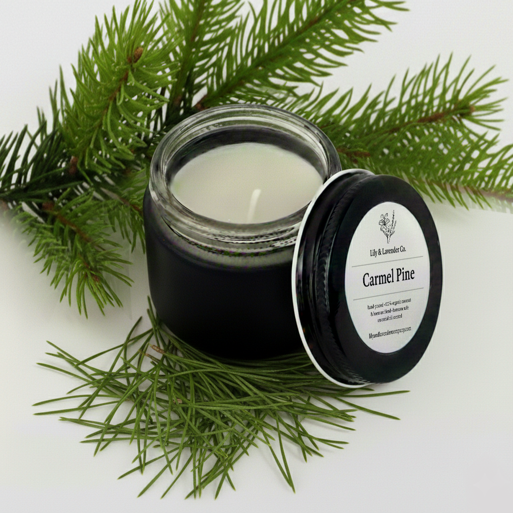 Lily & Lavender Co. Carmel Pine Essential Oil Scented, Non-Toxic Coconut & Beeswax Candle sitting with pine branches and pine cones.
