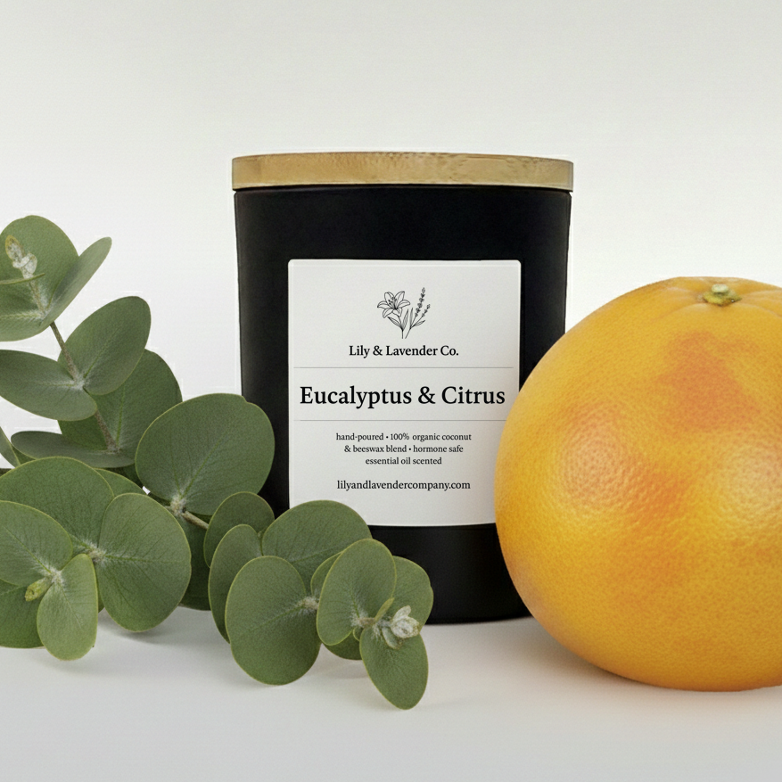Lily & Lavender Co. Eucalyptus & Citrus Essential Oil Scented, Non-Toxic Coconut & Beeswax Candle sitting with and grapefruit and eucalyptus branch.