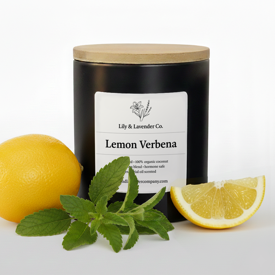 Lily & Lavender Co. Lemon Verbena, Essential Oil Scented, Non-Toxic Coconut & Beeswax Candle surrounded by a lemon, piece of lemon, and Lemon verbena bushel.