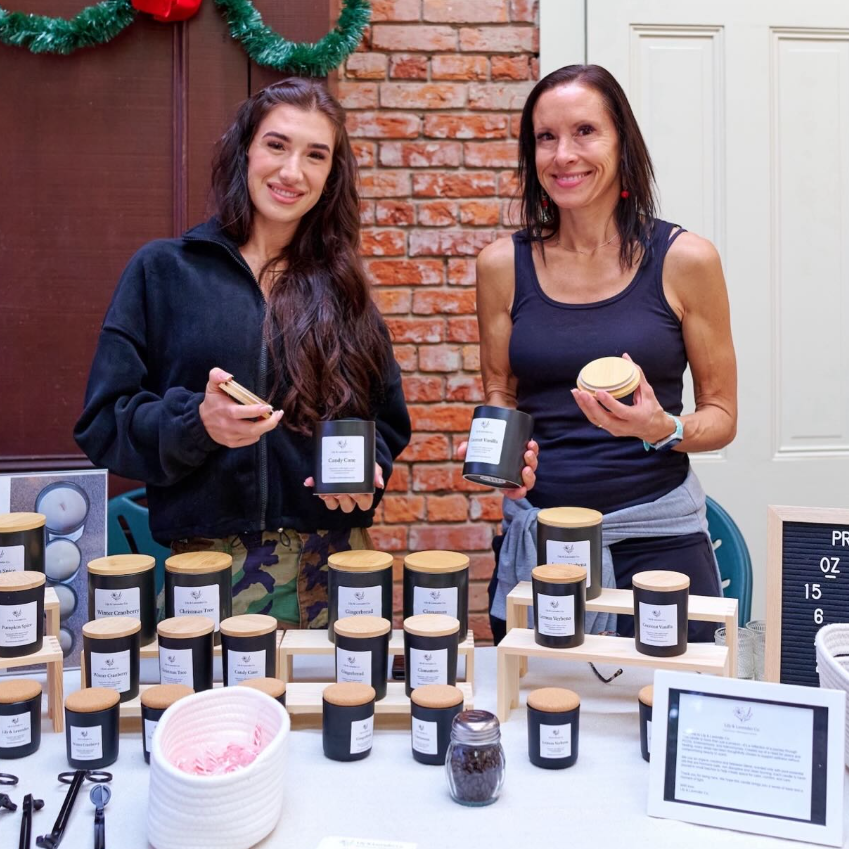 Jacey & Amy Vickrey holding candles in front of a display of Lily and Lavender co non-toxic candles in Carmel, CA.