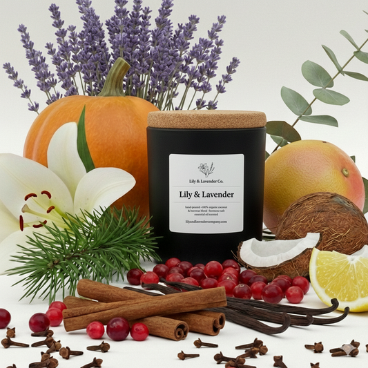 Candle labeled 'Lily & Lavender' surrounded by pumpkins, lavender, lily, coconuts, lemons, cranberries, cloves, cinnamon, vanilla beans, and spices on a white background.