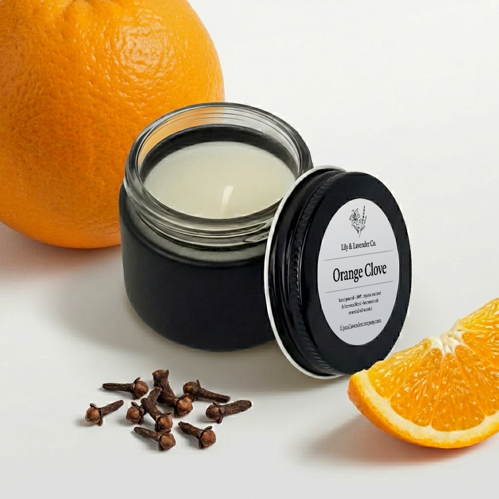 Lily & Lavender Co. Orange & Clove Essential Oil Scented, Non-Toxic Coconut & Beeswax Candle sitting with and orange and cloves.