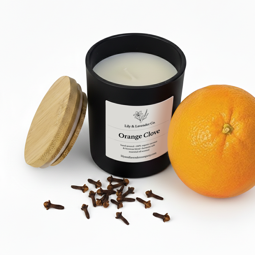 Lily & Lavender Co. Orange & Clove Essential Oil Scented, Non-Toxic Coconut & Beeswax Candle sitting with and orange and cloves.