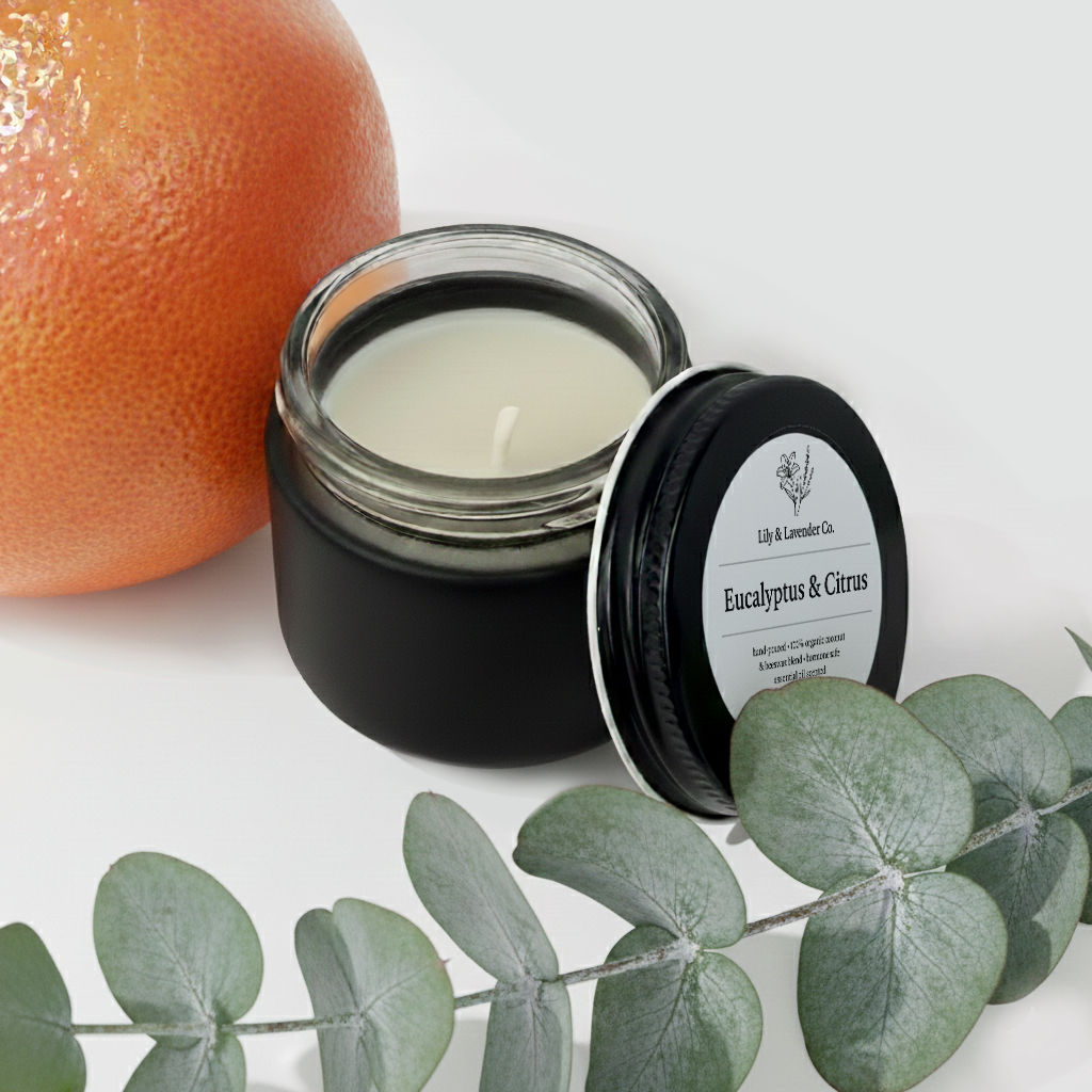 Lily & Lavender Co. Eucalyptus & Citrus Essential Oil Scented, Non-Toxic Coconut & Beeswax Candle sitting with and grapefruit and eucalyptus branch.